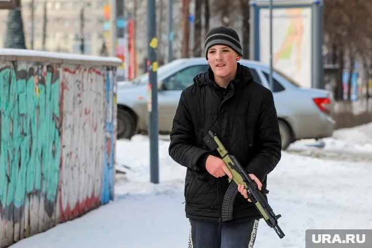 Молодой человек держит автомат наготове