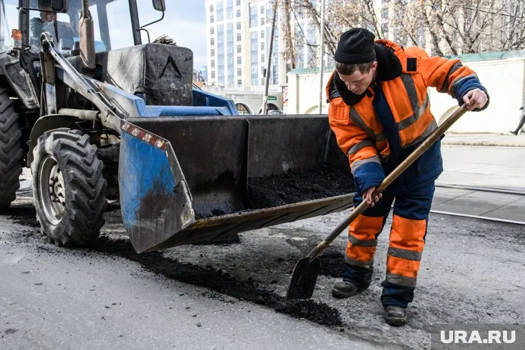 За неимением катка рабочие трамбуют асфальт ногами