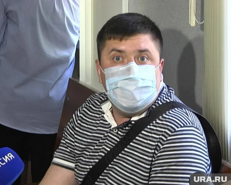 Денис Синяк скрывает лицо за медицинской маской