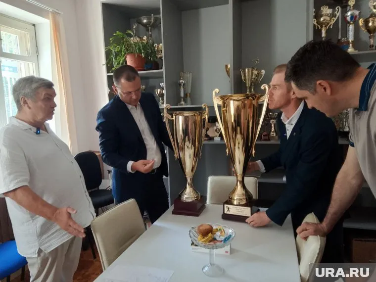 Николай Власов (слева) демонстрирует Кириллу Матвееву, Антону Рыжему и Александру Назарову кубки, завоеванные воспитанниками спортшколы