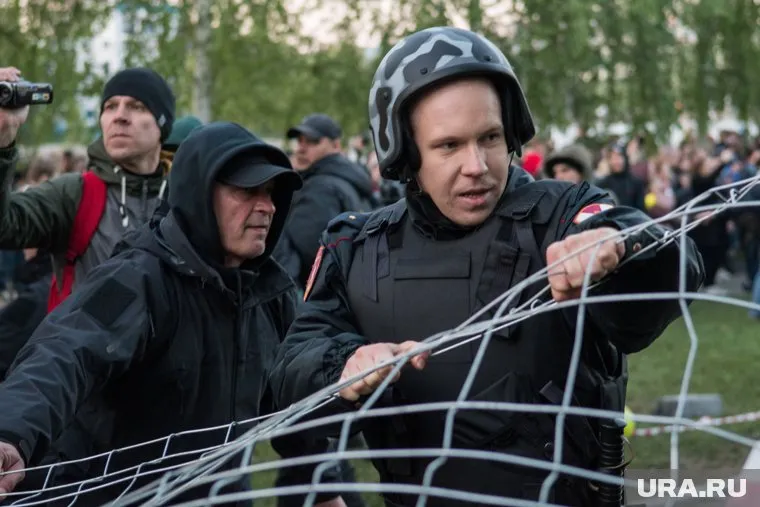 Полицейского Евгения Крюкова (слева) было не отличить от простых горожан. Однако он стоял за оцеплением