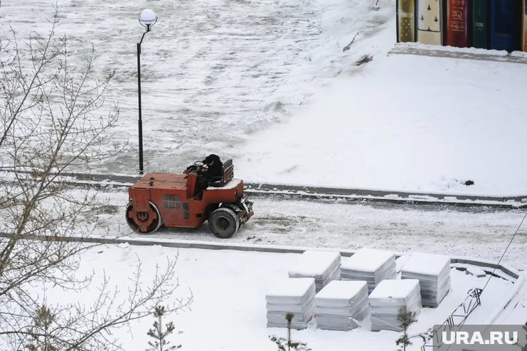 Каток трамбует щебень вместе со снегом