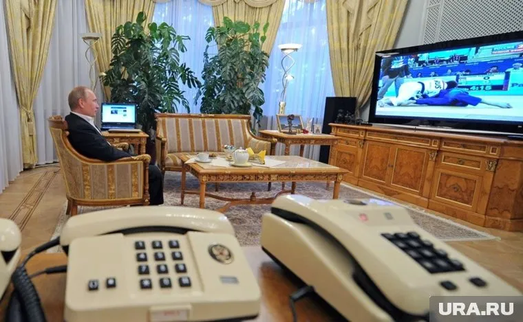 Телефон без кнопок и с гербом стоит на рабочем столе Владимира Путина