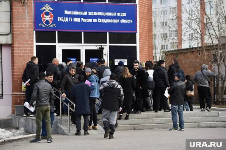 Сотрудники полиции выталкивают из отделения толпу иностранцев