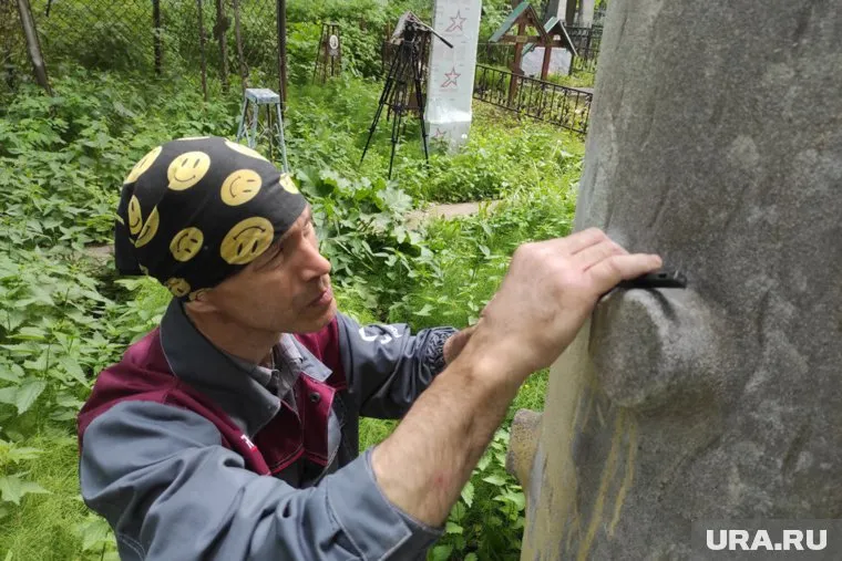 Илья Сидоров очищает от краски надгробие