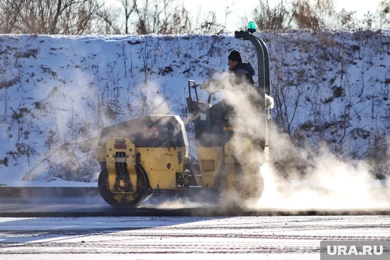В Тарко-Сале рабочие укладывают асфальт, несмотря на снежный покров